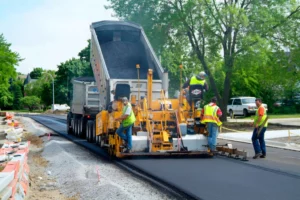 operai a lavoro nella costruzione di una strada, mentre seguono la fase di stesura dell'asfalto