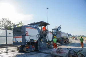 lavoratori dell'asfalto procedono con la fresatura e lo smaltimento dell'asfalto