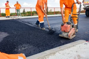 operai stendono l'asfalto sulla strada in costruzione